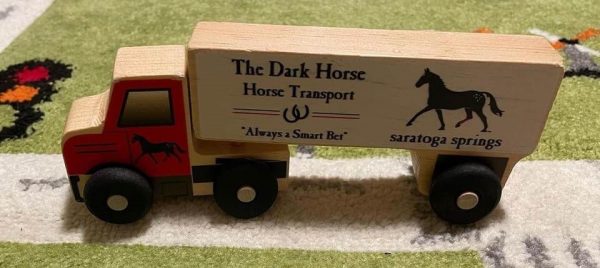 Wooden Semi Truck showing The Dark Horse Transport- Always a smart bet- a horse and Saratoga Springs- red front cab with horse on door- natural wood on rest of truck